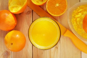 Oranges and glass of orange juice on cutting board